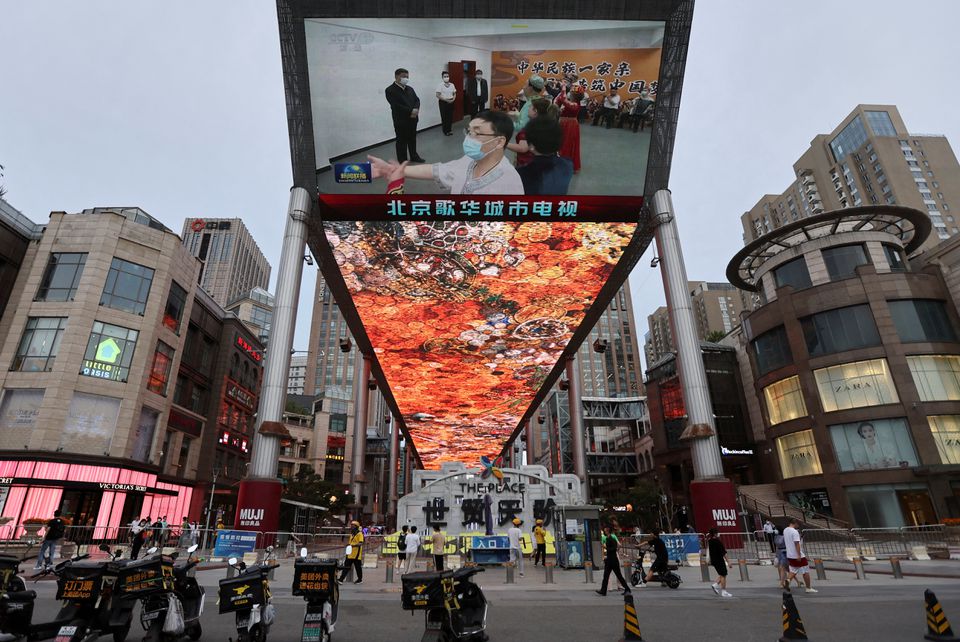 A giant screen shows news footage of Chinese President Xi Jinping visiting Xinjiang Uyghur Autonomous Region, at a shopping centre, in Beijing, China, July 15, 2022. REUTERS/Tingshu Wang/File Photo