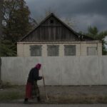 An elderly woman walks on a street in Raihorodok, Ukraine, Monday, Sept. 26, 2022. (AP Photo/Leo Correa)