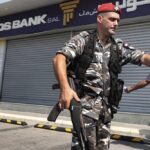 Lebanese security officers stand outside a Byblos Bank branch that was broken into by depositor Ali Hodroj holding a handgun, firing a warning shot and demanding about $40,000 of his trapped savings, in Tyre, south Lebanon, Tuesday, Oct. 4, 2022. Hodroj retrieved about $9,000 in Lebanese pounds following negotiations before he turned himself in to police outside the branch. Lebanese depositors, including a retired police officer, stormed at least four banks in the cash-strapped country Tuesday after banks ended a weeklong closure and partially reopened. (AP Photo/Mohammed Zaatari)