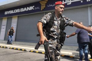 Lebanese security officers stand outside a Byblos Bank branch that was broken into by depositor Ali Hodroj holding a handgun, firing a warning shot and demanding about $40,000 of his trapped savings, in Tyre, south Lebanon, Tuesday, Oct. 4, 2022. Hodroj retrieved about $9,000 in Lebanese pounds following negotiations before he turned himself in to police outside the branch. Lebanese depositors, including a retired police officer, stormed at least four banks in the cash-strapped country Tuesday after banks ended a weeklong closure and partially reopened. (AP Photo/Mohammed Zaatari)