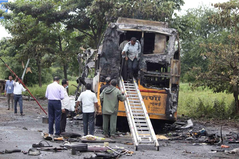 People inspect a bus that caught fire in a highway in Nashik, in the western Indian state of Maharashtra, Saturday, Oct. 8, 2022. The bus caught fire after hitting a truck on a highway in western India early Saturday, killing at least 12 passengers, said police officer Bhagwan Adke. Another 43 people with serious burns were taken to a hospital in Nashik. (AP Photo/Yatish Bhanu)