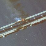 This infrared satellite image provided by Maxar Technologies shows damage to the Kerch Bridge, which connects the Crimean Peninsula with Russia crossing a strait between the Black Sea and the Sea of Azov, and rail cars on fire on Saturday, Oct. 8, 2022. (Maxar Technologies via AP)