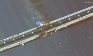 This infrared satellite image provided by Maxar Technologies shows damage to the Kerch Bridge, which connects the Crimean Peninsula with Russia crossing a strait between the Black Sea and the Sea of Azov, and rail cars on fire on Saturday, Oct. 8, 2022. (Maxar Technologies via AP)