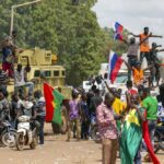 Supporters of Capt. Ibrahim Traore cheer with Russian flags in the streets of Ouagadougou, Burkina Faso, Sunday, Oct. 2, 2022. Burkina Faso’s new junta leadership is calling for calm after the French Embassy and other buildings were attacked. (AP Photo/Kilaye Bationo)