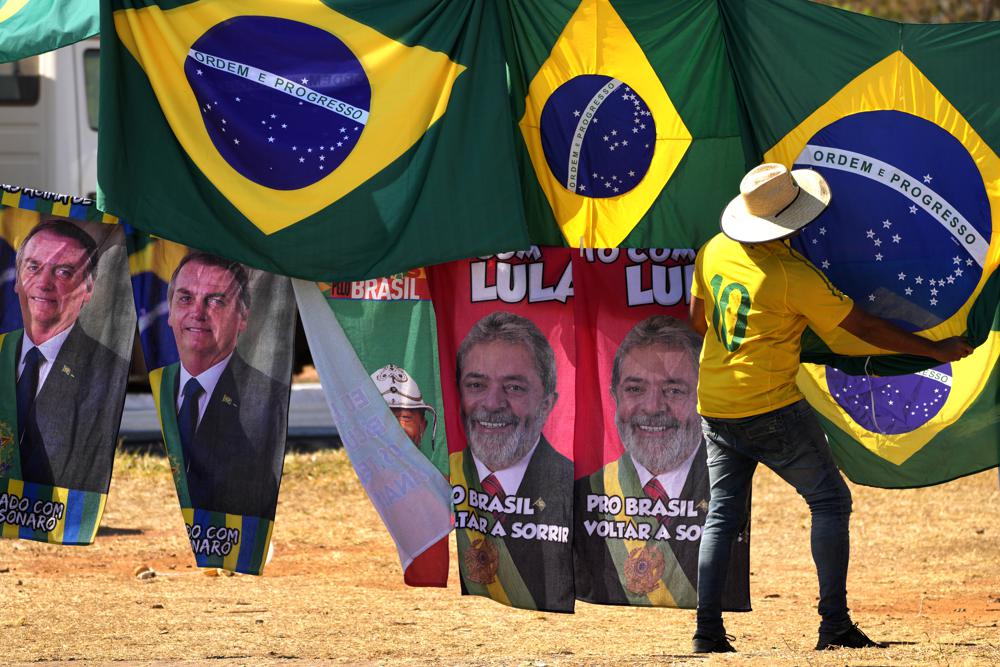 FILE – Presidential election campaign flags hang for sale, featuring the faces of both current President Jair Bolsonaro, left, and former President Luiz Inacio Lula da Silva, outside the Supreme Electoral Court in Brasilia, Brazil, Sept. 5, 2022. Bolsonaro will face da Silva in the Oct. 30 runoff for president. (AP Photo/Eraldo Peres, File)