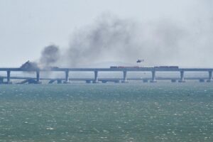 A helicopter flies to drop water to stop fire on Crimean Bridge connecting Russian mainland and Crimean peninsula over the Kerch Strait, in Kerch, Crimea, Saturday, Oct. 8, 2022. Russian authorities say a truck bomb has caused a fire and the collapse of a section of a bridge linking Russia-annexed Crimea with Russia. The bridge is a key supply artery for Moscow’s faltering war effort in southern Ukraine. (AP Photo)