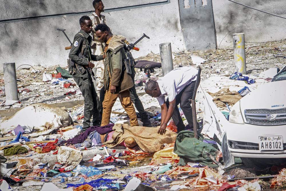 EDS NOTE: GRAPHIC CONTENT – Rescuers and security forces stand by a dead body at the scene of a double car-bomb attack in Mogadishu, Somalia, Saturday Oct. 29, 2022. Two car bombs exploded Saturday at a busy junction in Somalia’s capital near key government offices, leaving “scores of civilian casualties,” police told state media. (AP Photo/Farah Abdi Warsameh)