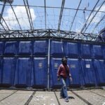 A man walks in front of gate at the Kanjuruhan Stadium in Malang, Indonesia, Tuesday, Oct. 4, 2022. A police chief and nine elite officers were removed from their posts Monday and 18 others were being investigated for responsibility in the firing of tear gas inside a soccer stadium that set off a stampede, killing over 100 people, officials said. (AP Photo/Achmad Ibrahim)