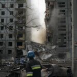 A firefighter looks at a part of a wall falling from the residential building that was heavily damaged after a Russian attack in Zaporizhzhia, Ukraine, Sunday, Oct. 9, 2022. (AP Photo/Leo Correa)