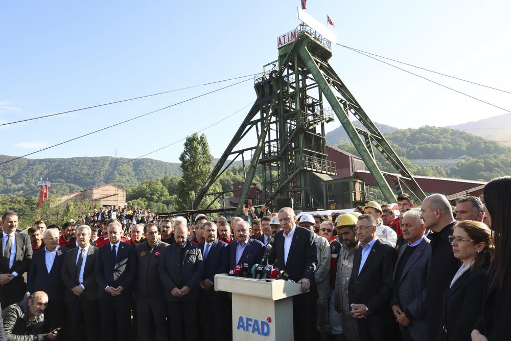 Turkey’s President Recep Tayyip Erdogan, center, is surrounded by his ministers as he speaks to the media outside the coal mine in Amasra, in the Black Sea coastal province of Bartin, Turkey, Saturday, Oct. 15, 2022. Funerals for miners killed in a coal mine explosion in northern Turkey began Saturday as officials raised the death toll to at least 40 people. There were 110 miners working several hundred meters below ground when the explosion occurred Friday evening. (Turkish Presidency via AP )