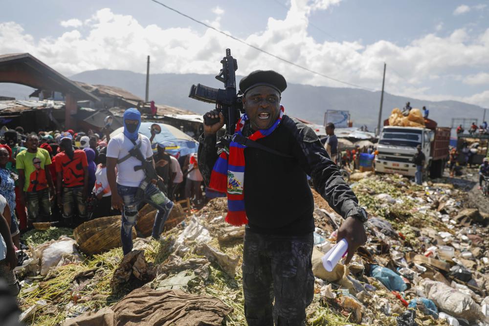 FILE – Barbecue, the leader of the “G9 and Family” gang, stands next to garbage to call attention to the conditions people live in as he leads a march against kidnapping through La Saline neighborhood in Port-au-Prince, Haiti, Friday, Oct. 22, 2021. Haiti Prime Minister Ariel Henry and 18 top-ranking officials have requested on the second week of Oct. 2022, the immediate deployment of foreign armed troops as gangs and protesters paralyze the country. (AP Photo/Odelyn Joseph, File)