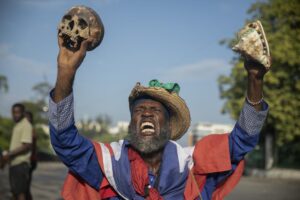 A protester holding up a skull and seashell shouts for the resignation of Haitian Prime Minister Ariel Henry in the street in the Champs de Mars area where the prime minister attended a ceremony marking the death anniversary of revolutionary leader Jean-Jacques Dessalines in Port-au-Prince, Haiti, Monday, Oct. 17, 2022. (AP Photo/Odelyn Joseph)