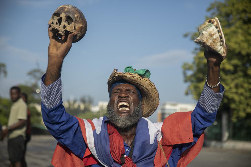 A protester holding up a skull and seashell shouts for the resignation of Haitian Prime Minister Ariel Henry in the street in the Champs de Mars area where the prime minister attended a ceremony marking the death anniversary of revolutionary leader Jean-Jacques Dessalines in Port-au-Prince, Haiti, Monday, Oct. 17, 2022. (AP Photo/Odelyn Joseph)