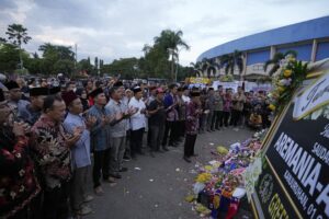 Supporters of soccer club Arema FC pray for victims of Saturday’s soccer match stampede outside the Kanjuruhan Stadium in Malang, Indonesia, Monday, Oct. 3, 2022. Panic at an Indonesian soccer match Saturday left over 100 people dead, most of whom were trampled to death after police fired tear gas to stop the violence. (AP Photo/Achmad Ibrahim)