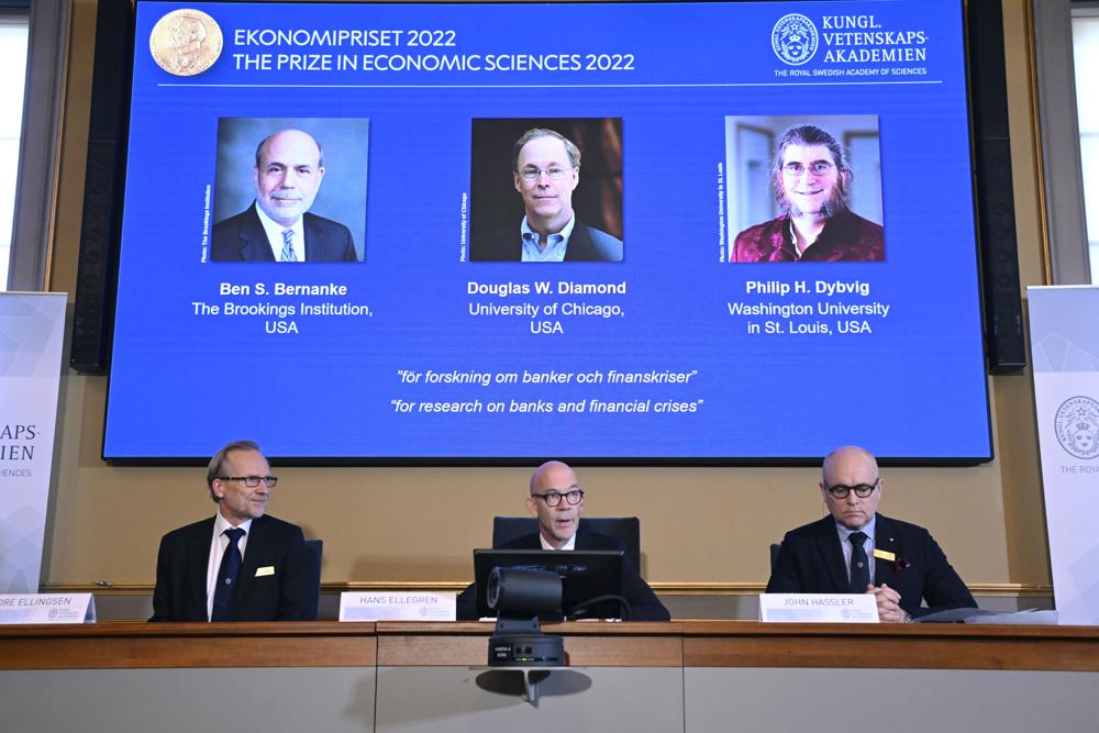 From left, Tore Ellingsen, Hans Ellegren and John Hassler members of the Royal Swedish Academy of Sciences announce the Sveriges Riksbank Prize in Economic Sciences in Memory of Alfred Nobel 2022, during a press conference at the Royal Swedish Academy of Sciences in Stockholm, Sweden, Monday, Oct. 10, 2022. From left on screen Ben S. Bernanke, Douglas W. Diamond and Philip H. Dybvig have been awarded 2022’s Nobel Prize in economic sciences. (Anders Wiklund/TT News Agency via AP)