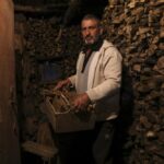 Gheorghe Batca carries firewood from a storage room to his house outside Chisinau, Moldova, Sunday, Oct. 16, 2022. Europe’s energy crisis, triggered by Russia slashing natural gas flows amid its war against Ukraine, has forced some people to turn to cheaper heating sources like firewood as the weather gets colder. But as more people stock up and burn wood, prices have skyrocketed, shortages and thefts have been reported, and scams are emerging. (AP Photo/Aurel Obreja)