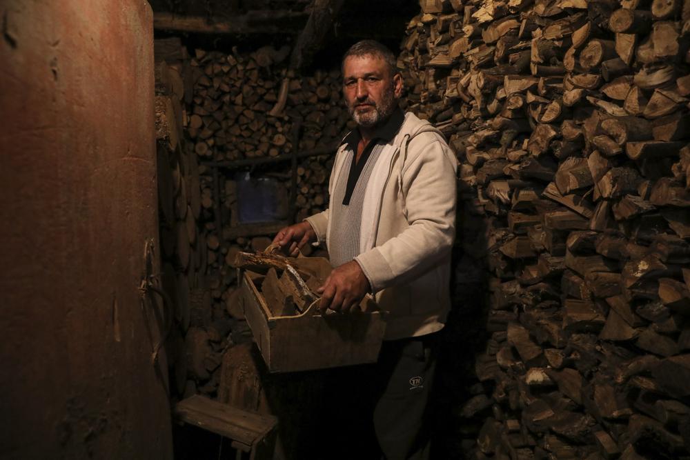 Gheorghe Batca carries firewood from a storage room to his house outside Chisinau, Moldova, Sunday, Oct. 16, 2022. Europe’s energy crisis, triggered by Russia slashing natural gas flows amid its war against Ukraine, has forced some people to turn to cheaper heating sources like firewood as the weather gets colder. But as more people stock up and burn wood, prices have skyrocketed, shortages and thefts have been reported, and scams are emerging. (AP Photo/Aurel Obreja)