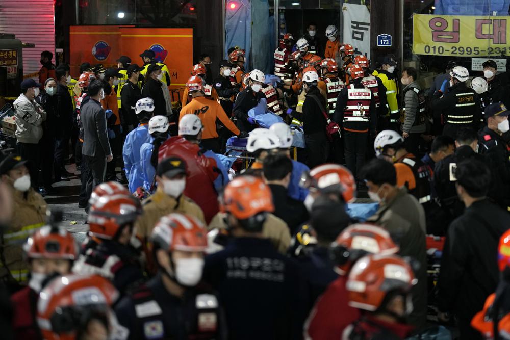 Rescue workers try to carry victims on the street near the scene, in Seoul, South Korea, Sunday, Oct. 30, 2022. South Korean officials say at least 120 people were killed and 100 more were injured as they were crushed by a large crowd pushing forward on a narrow street during Halloween festivities in the capital of Seoul. Choi Seong-beom, chief of Seoul’s Yongsan fire department, said the death toll could rise, saying that an unspecified number among the injured were in critical conditions. (AP Photo/Lee Jin-man)
