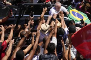 Former Brazilian President Luiz Inacio Lula da Silva, center, who is running for president again, hold hands with a supporter after voting in a presidential run-off election in Sao Paulo, Brazil, Sunday, Oct. 30, 2022. (AP Photo/Andre Penner)