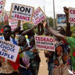 Supporters of Capt. Ibrahim Traore protest against France and the West African regional bloc known as ECOWAS in the streets of Ouagadougou, Burkina Faso, Tuesday, Oct. 4, 2022. A meeting of West African regional mediators stepping up pressure on the country’s new junta comes amid fears that the second coup to hit the country this year will further delay democratic elections and a return to civilian rule. (AP Photo/Kilaye Bationo)