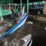 Fishermen look at boats partially submerged in water after Hurricane Julia swept through the area in Bluefields, Nicaragua, Sunday, Oct. 9, 2022. Hurricane Julia hit Nicaragua’s central Caribbean coast and dumped torrential rains across Central America before reemerging over the Pacific as a tropical storm. (AP Photo/Inti Ocon)