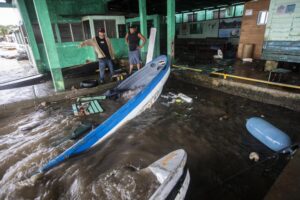 Fishermen look at boats partially submerged in water after Hurricane Julia swept through the area in Bluefields, Nicaragua, Sunday, Oct. 9, 2022. Hurricane Julia hit Nicaragua’s central Caribbean coast and dumped torrential rains across Central America before reemerging over the Pacific as a tropical storm. (AP Photo/Inti Ocon)