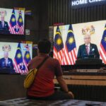 A customer watches a live broadcast of an announcement by Malaysian Prime Minister Ismail Sabri Yaakob at an electronics store in Kuala Lumpur, Monday, Oct. 10, 2022. Ismail announced Monday that Parliament will be dissolved, paving the way for general elections. (AP Photo/Vincent Thian)