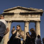 A tourists takes a selfie in front the Gate of the ancient Roman agora, in Plaka, district of Athens, on Thursday, Oct.13, 2022. Greece is on course to beat its annual record for tourism revenue as southern European Union members made a surprise recovery following a two-year travel slump caused by the pandemic. (AP Photo/Petros Giannakouris)