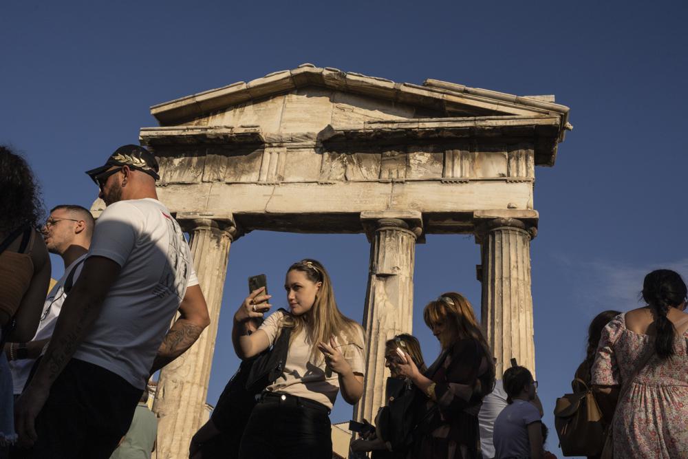 A tourists takes a selfie in front the Gate of the ancient Roman agora, in Plaka, district of Athens, on Thursday, Oct.13, 2022. Greece is on course to beat its annual record for tourism revenue as southern European Union members made a surprise recovery following a two-year travel slump caused by the pandemic. (AP Photo/Petros Giannakouris)