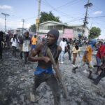 FILE – A protester carries a piece of wood simulating a weapon during a protest demanding the resignation of Prime Minister Ariel Henry, in the Petion-Ville area of Port-au-Prince, Haiti, Oct. 3, 2022. Haiti’s government has agreed to request the help of international armed forces as gangs and protesters paralyze the country and basic supplies including fuel and water dwindle, a top ranking Haitian official told The Associated Press on Friday, Oct 7. (AP Photo/Odelyn Joseph, File)