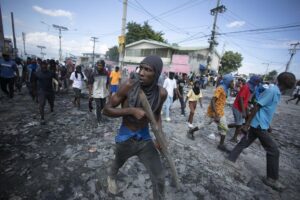 FILE – A protester carries a piece of wood simulating a weapon during a protest demanding the resignation of Prime Minister Ariel Henry, in the Petion-Ville area of Port-au-Prince, Haiti, Oct. 3, 2022. Haiti’s government has agreed to request the help of international armed forces as gangs and protesters paralyze the country and basic supplies including fuel and water dwindle, a top ranking Haitian official told The Associated Press on Friday, Oct 7. (AP Photo/Odelyn Joseph, File)