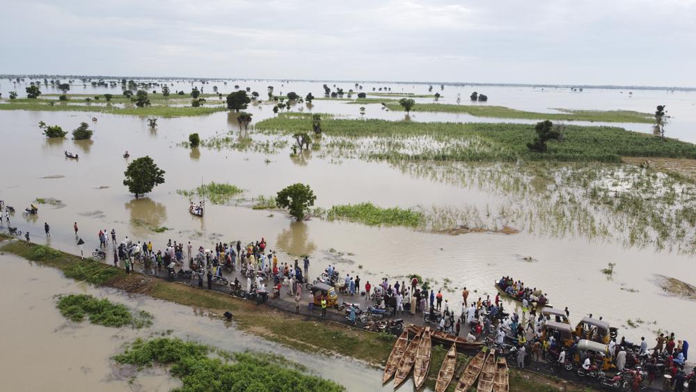 FILE – People walk through floodwaters with flooded farmlands forground after heavy rainfall in Hadeja, Nigeria, Sept 19, 2022. West and Central African countries are battling deadly floods that have upended lives and livelihoods, raising fears of further disruption of food supplies in many areas battling armed conflict. “Above-average rainfall and devastating flooding” have affected 5 million people this year in 19 countries across West and Central Africa, according to a new U.N. World Food Program situation report. (AP Photo, file)