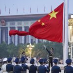 In this photo released by Xinhua News Agency, a member of the Chinese honor guard unfurls the Chinese national flag during a flag raising ceremony to mark the 73rd anniversary of the founding of the People’s Republic of China held at the Tiananmen Square in Beijing on Saturday, Oct. 1, 2022. (Chen Zhonghao/Xinhua via AP)