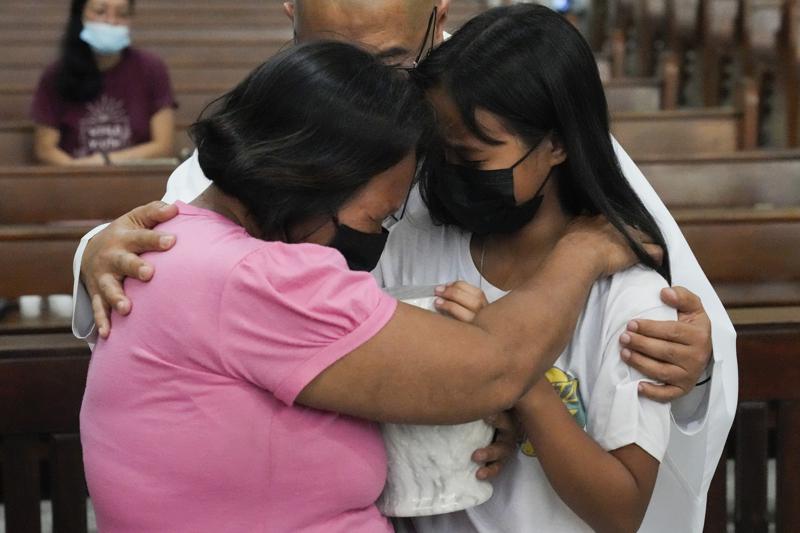 Catholic priest Flaviano “Flavie” Villanueva comforts relatives as they receive the urn containing the remains of victims of alleged extrajudicial killings at a church in Quezon city, Philippines, Wednesday, Sept. 28, 2022. A program was created to assist in getting a final resting place for exhumed remains of alleged victims of former Philippine President Rodrigo Duterte’s “war on drugs.” (AP Photo/Aaron Favila)