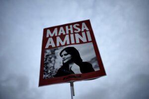 FILE – A woman holds a placard with a picture of Iranian woman Mahsa Amini during a protest against her death, in Berlin, Germany, Wednesday, Sept. 28, 2022. Iranian celebrities have been startlingly public in their support for the massive anti-government protests shaking their country. And the ruling establishment is lashing back. Celebrities have found themselves targeted for arrest, have had passports confiscated and faced other harassment. (AP Photo/Markus Schreiber, File)