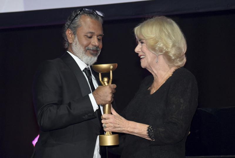 Britain’s Camilla, Queen Consort, presents winner Shehan Karunatilaka with the trophee for “The Seven Moons of Maali Almeida” during the Booker Prize at the Roundhouse in London, Monday Oct. 17, 2022. (Toby Melville/Pool Photo via AP)