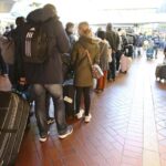 Travelers stand in long lines at the travel center in Hamburg Central Station after long-distance services in northern Germany came to a standstill, Hamburg, Germany, Saturday, Oct.8, 2022. According to Deutsche Bahn, a technical fault in northern Germany is currently causing a complete standstill in long-distance services. All ICE as well as IC and EC trains in northern Germany are affected, (Bodo Marks/dpa via AP)