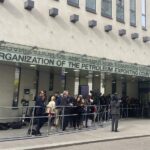 FILE – People and media gather at the entrance of the building of the Organization of the Petroleum Exporting Countries, OPEC, in Vienna, Austria on Oct. 5, 2022. Saudi Arabia said Thursday, Oct. 13, 2022 that the U.S. had urged the kingdom to postpone a decision by OPEC and its allies, including Russia, to cut oil production by a month which would have been just before the upcoming American midterm elections. (AP Photo/Philipp-Moritz Jenne, File)