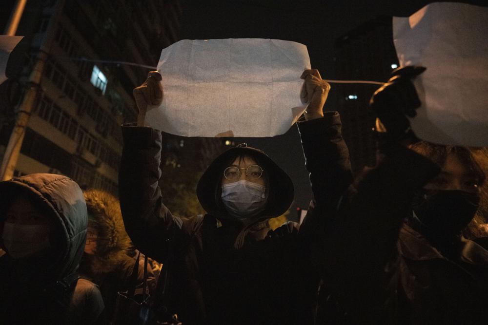 A protestor holds up a blank paper and chant slogans during a march in protest in Beijing, Sunday, Nov. 27, 2022. Protesters angered by strict anti-virus measures called for China’s powerful leader to resign, an unprecedented rebuke as authorities in at least eight cities struggled to suppress demonstrations Sunday that represent a rare direct challenge to the ruling Communist Party. (AP Photo/Ng Han Guan)