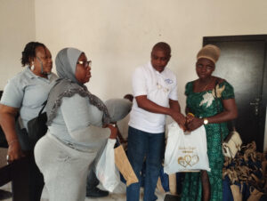 In the middle, Shitta-Bey handing over food items to one of the beneficiaries