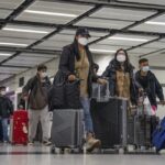Travelers wearing face masks with their luggage head to the immigration counter at the departure hall at Lok Ma Chau station following the reopening of crossing border with mainland China, in Hong Kong, Sunday, Jan. 8, 2023. Travelers crossing between Hong Kong and mainland China, however, are still required to show a negative COVID-19 test taken within the last 48 hours, a measure China has protested when imposed by other countries. (AP Photo/Bertha Wang)