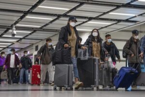Travelers wearing face masks with their luggage head to the immigration counter at the departure hall at Lok Ma Chau station following the reopening of crossing border with mainland China, in Hong Kong, Sunday, Jan. 8, 2023. Travelers crossing between Hong Kong and mainland China, however, are still required to show a negative COVID-19 test taken within the last 48 hours, a measure China has protested when imposed by other countries. (AP Photo/Bertha Wang)