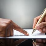person-signing-document-pointing-finger-front-golden-pen-126325287