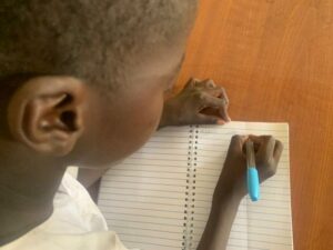 Primary 1 pupil Abba Mustapha writing his name