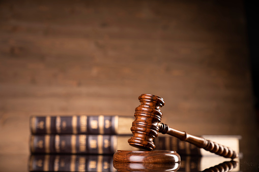 Judge’s gavel and collection of legal books on brown background.