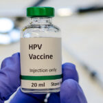HPV vaccine vial with syringe and stethoscope at the background
