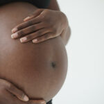 Midsection of pregnant Black woman holding belly