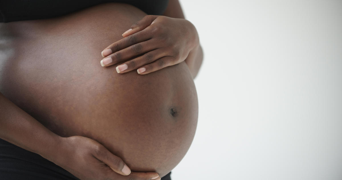 Midsection of pregnant Black woman holding belly