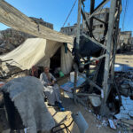 Displaced Palestinians, who fled their house due to Israel’s military offensive, sit outside their tent, in Rafah, in the southern Gaza Strip