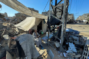 Displaced Palestinians, who fled their house due to Israel’s military offensive, sit outside their tent, in Rafah, in the southern Gaza Strip